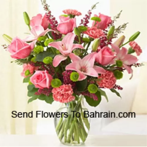 Rosa Rosen, rosa Nelken und rosa Lilien mit verschiedenen Farnen und Füllstoffen in einer Glasvase