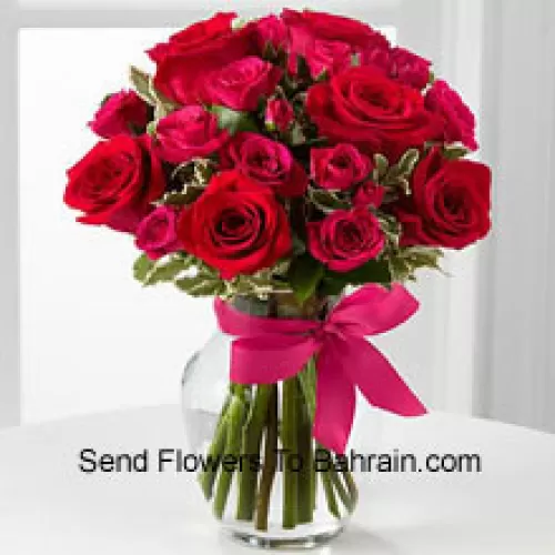 18 Rosas rojas con relleno de temporada en un jarrón de vidrio decorado con un moño rosa